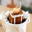 Fresh Burundi Turihamwe Farms coffee pour over packet displayed on wooden surface with coffee beans and brewing equipment