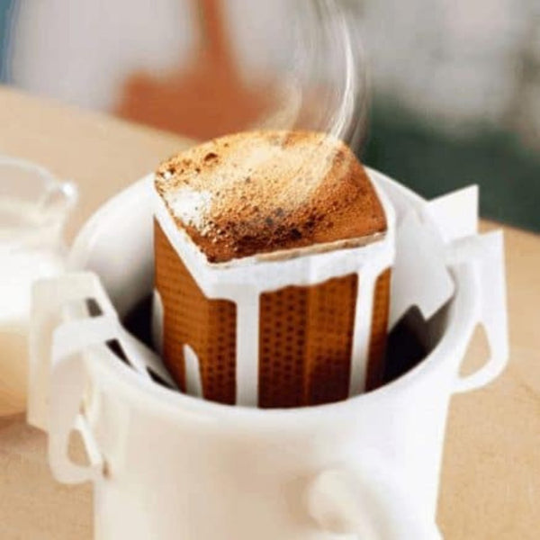 Fresh Burundi Turihamwe Farms coffee pour over packet displayed on wooden surface with coffee beans and brewing equipment