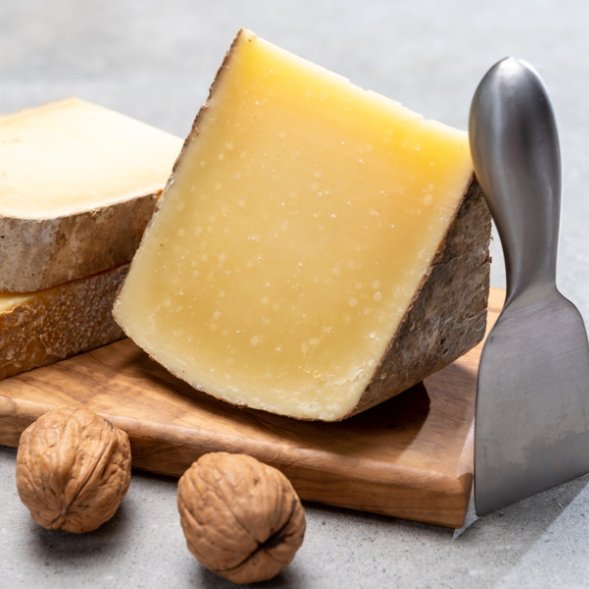 Comte cheese aged 24 months with rich golden texture, artisanal French hard cheese displayed on wooden board