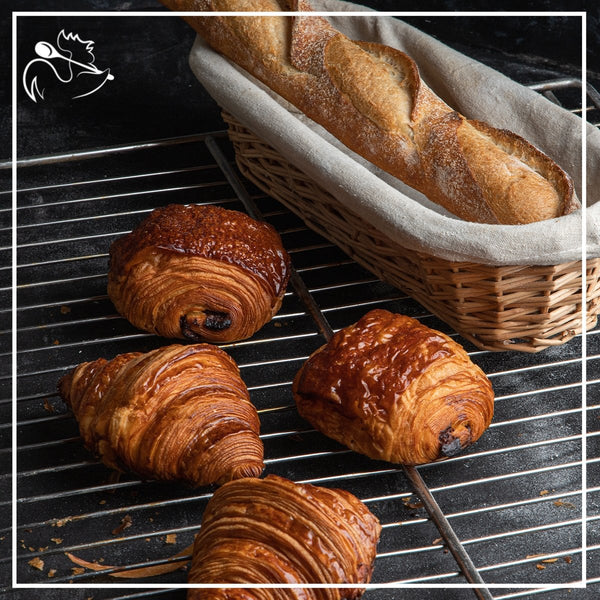 Continental breakfast with fresh croissants, coffee, juice, and fruits served on a wooden table for a delightful morning meal