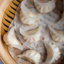 Mixed seafood dumplings in a clear package showing 24 frozen pieces with various seafood fillings, ready to cook