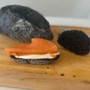 Freshly baked artisan bread with activated charcoal, featuring a dark crust and rustic texture on wooden surface