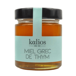 Pure Greek thyme honey in a glass jar with wooden dipper, featuring natural amber color and medicinal properties