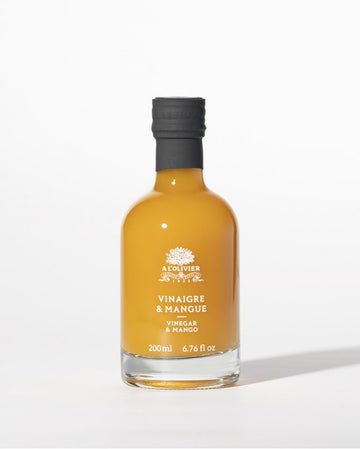 A bottle of À L'Olivier Vinegar & Mango, featuring a luxurious amber-colored fruit vinegar infusion in elegant packaging