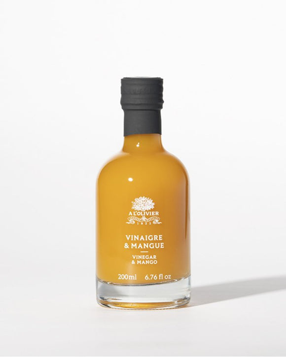 A bottle of À L'Olivier Vinegar & Mango, featuring a luxurious amber-colored fruit vinegar infusion in elegant packaging
