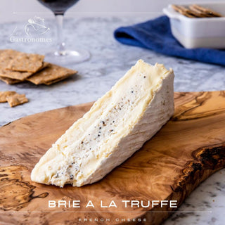 Delicious brie de Meaux cheese with black truffle pieces, creamy French specialty on wooden board, gourmet appetizer