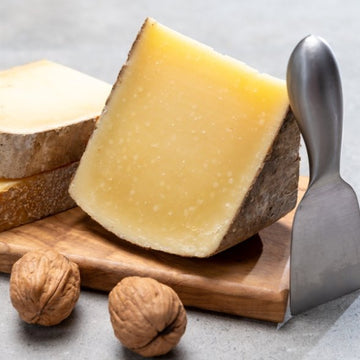 Comte cheese aged 24 months with rich golden texture, artisanal French hard cheese displayed on wooden board