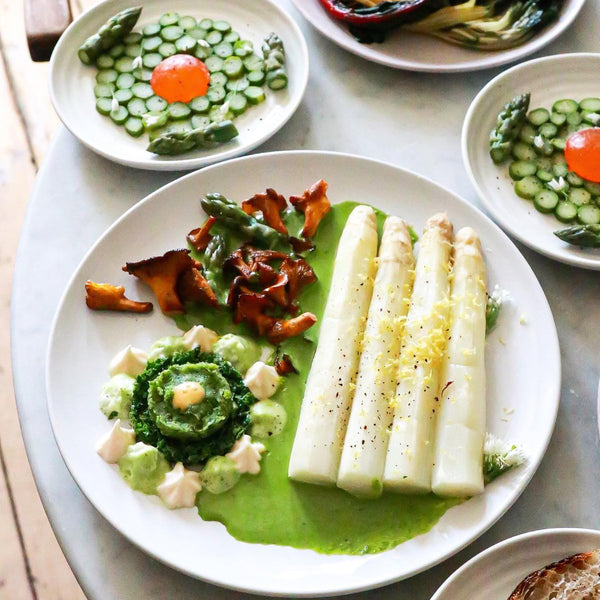 Fresh white asparagus with thick stalks, caliber 22+, bundled together on wooden surface, ready for cooking