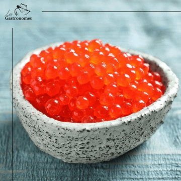 Delicious wild salmon caviar in a transparent container, showing vibrant orange-red roe pearls, perfect for gourmet appetizers